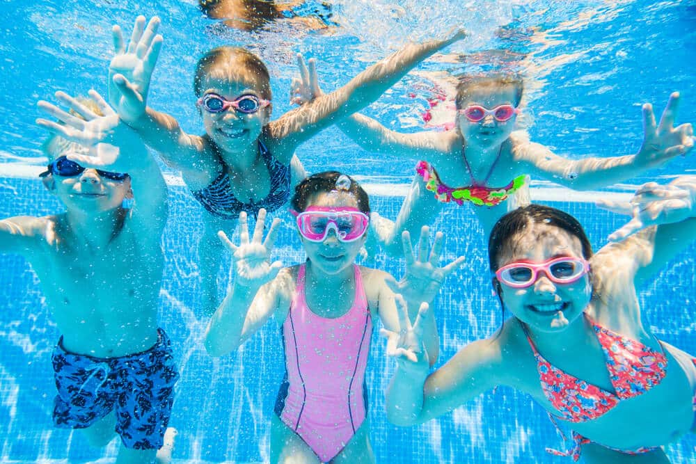 little kids swimming in pool underwater - Protecting Your Children from the Summer Heat