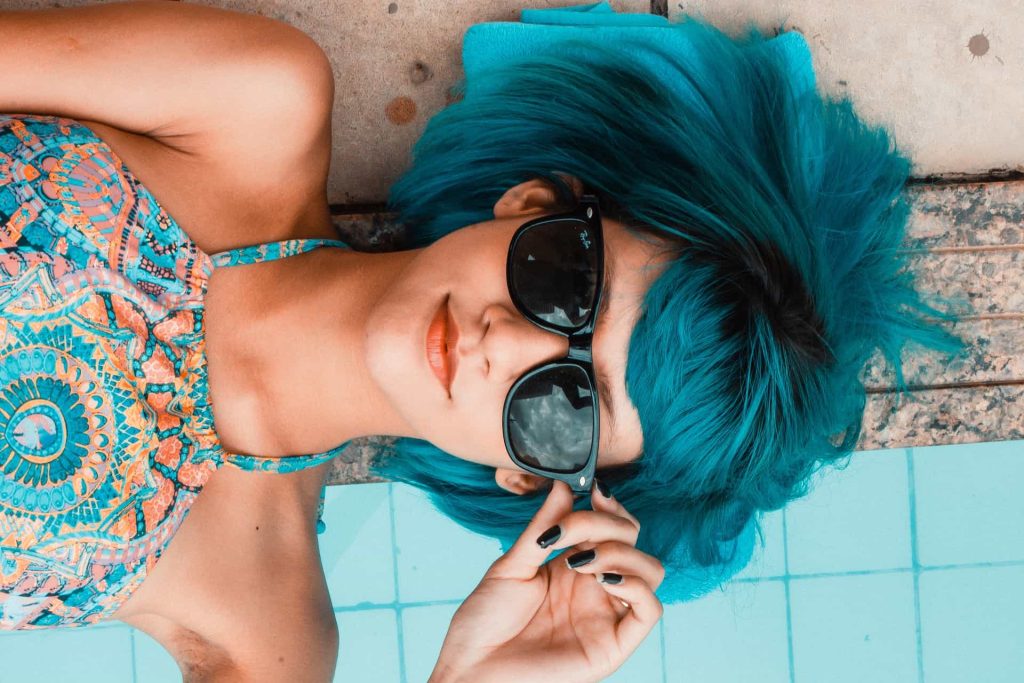Close up of blue hair girl laying on the edge of pool - Pool Covers Can Help Save Energy Costs